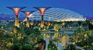 An overview of The Gardens by the Bay nature park in Singapore. The image showcases the parks diverse plant life, water features, greenhouse, and large tree-shaped towers.