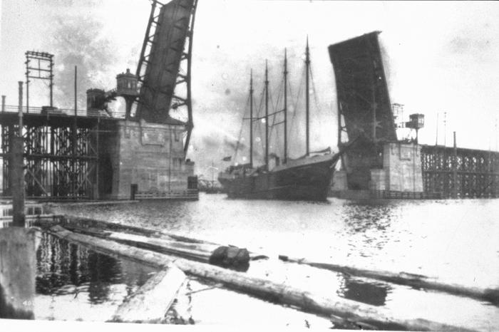 A drawbridge is open, with a tall ship passing through.