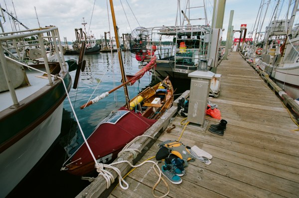 The dory is squeezed between two large fishing boats with more fishing boats all around. The author and his friends clothing and stuff are strewn about the boat and dock.