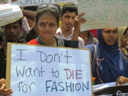 A group of protesters rally for safer working conditions in the garment industry. A woman with a focused gaze holds a sign that reads, "I don't want to die for fashion.