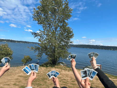 Alt text: NOAA Science Camp campers use a polaroid camera to take photos and hold up them up to show what science means to them.