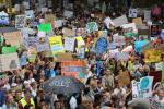 A large group of young people protest climate change and carry signs that read "One Earth One Chance" and "Climate Action Now" among others.