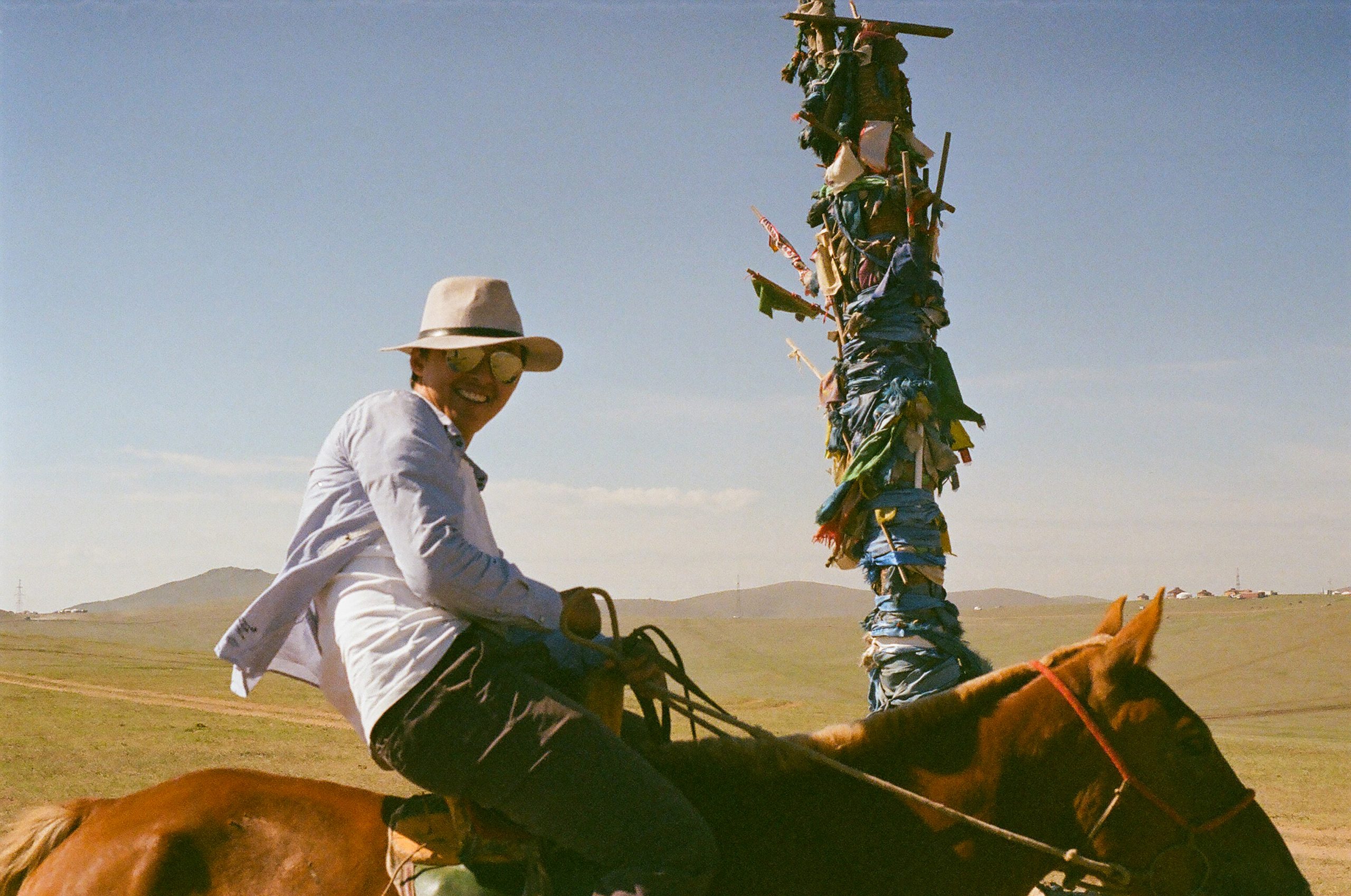 A smiling figure rides a horse with ease and swagger besides a religious monument.