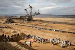 In Germany, lines of people stand at a coal mine and block a large piece of heavy mining machinery.
