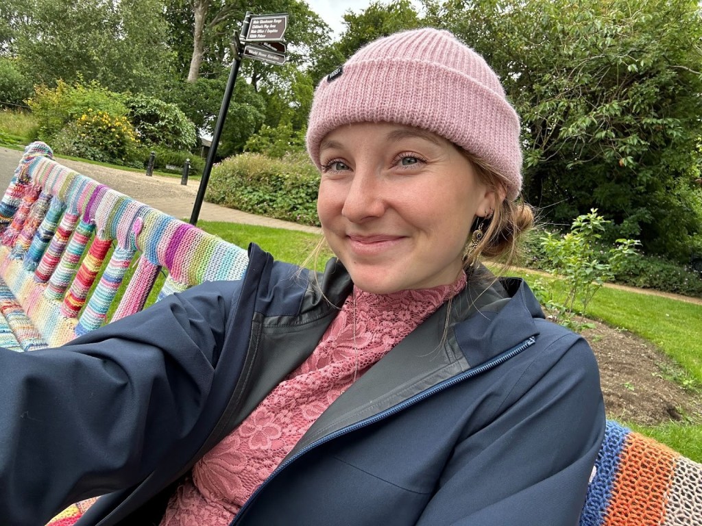 Alt text: a photo of Maddie Gard smiling near a colorful bench.