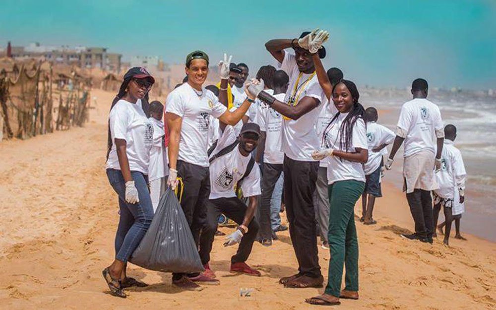 Alt text: Babacar Thiaw and other community members participating in a beach cleanup at his home beach of Plage du Virage.